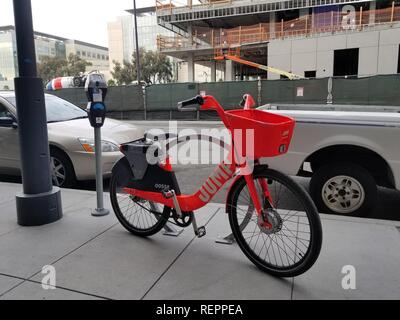 Nahaufnahme einer orange Fahrrad durch die Fahrt im Besitz-sharing Unternehmen springen, auf dem Bürgersteig geparkt Neben einem Fahrrad stehen auf der 3. Straße, gegenüber von Ucsf arbeitsmedizinischen Diensten, in der Mission Bay District von San Francisco, Kalifornien, 29. Oktober 2018. () Stockfoto