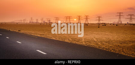 Malerischer Blick auf Sonnenuntergang über Stromleitungen in der Wüste in Dubai, VAE Stockfoto