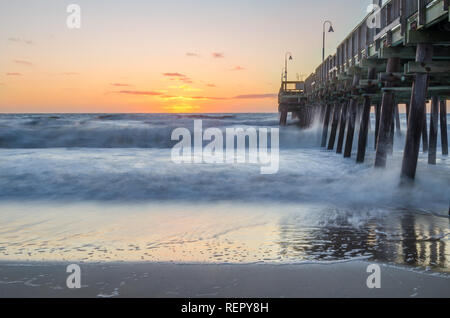 Wellen bei Sonnenaufgang am Sandbridge Fishing Pier in Virginia Beach, Virginia Stockfoto