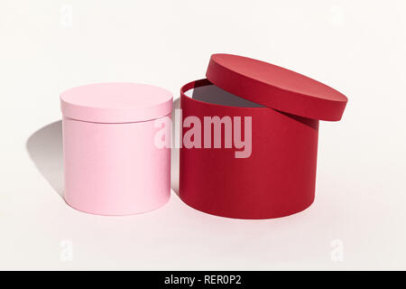 Schöne rosa und rote runde Geschenkbox für die Verpackung eine Überraschung mit einem geschlossenen Deckel close-up auf einem weißen Hintergrund. Stockfoto