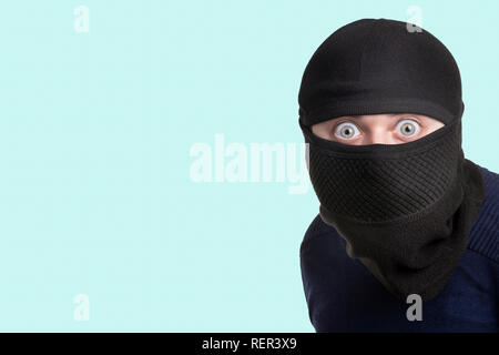 Mann in einem Balaclava auf einem blauen Hintergrund, Konzept des Verfangens ein Verbrecher am Tatort Stockfoto