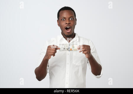 Afrikanische Mann im weißen Hemd hält hundert Dollar in seine Hände in die Kamera schaut Stockfoto