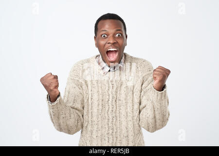 Portrait der Afrikanischen jungen gutaussehenden Mann überrascht mit Nachrichten, die er erhielt. Stockfoto