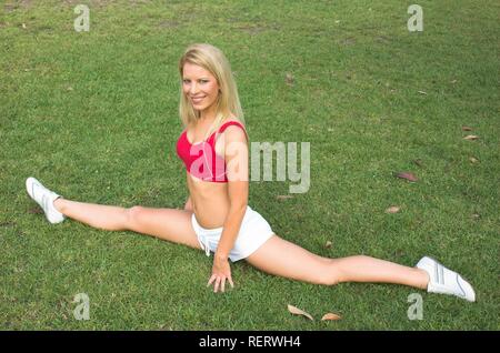 Eine hübsche junge blonde Frau, die den Spagat zu tun Stockfoto