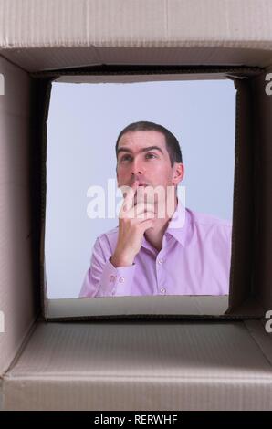 Nachdenkliche Menschen durch eine Box gesehen, symbolisch für Querdenken, kreatives Denken und Querdenken Stockfoto