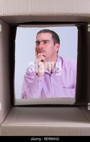 Nachdenkliche Menschen durch eine Box gesehen, symbolisch für Querdenken, kreatives Denken und Querdenken Stockfoto