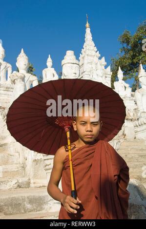 Junger buddhistischer Mönch mit einem roten Regenschirm, Settawya Pagode, Mingun, Burma, Myanmar, Südostasien Stockfoto