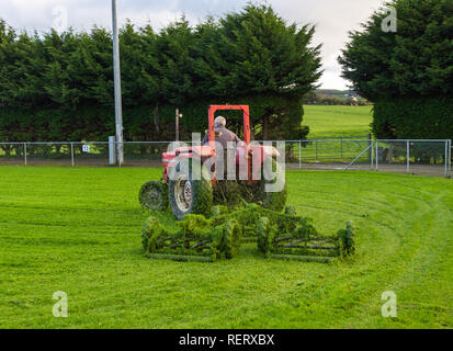 Mann auf einem Traktor, der beim Ziehen einer Bande Mäher Stockfoto