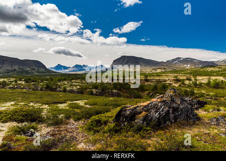 Ein Blick auf die felsigen und steinigen Gelände mit Wolken mit Bergen im Hintergrund. Norwegen, Rondane Nationalpark Stockfoto