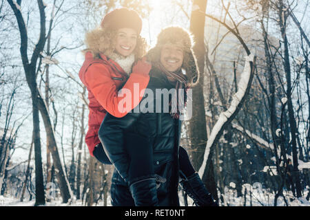 Mann, der seine Frau huckepack an einem Wintertag Stockfoto