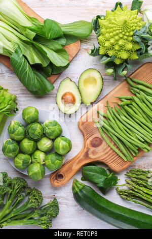 Saubere Konzept essen. Grünes Gemüse am weißen Tisch brokkolisprößlinge Erbsen avocado Zucchini Bohnen Bok choy Sellerie, Ansicht von oben, selektiver Fokus Stockfoto