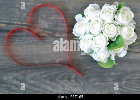 Blumenstrauß aus den weißen Rosen Nahaufnahme mit Band in Form eines Herzen Farbe der Koralle leben auf einem Holz- vintage Hintergrund. Romantische Karte Konzept. Der vi. Stockfoto