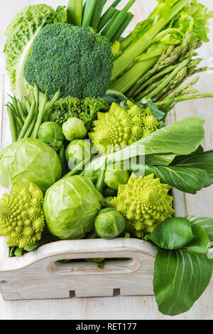 Gesunde Ernährung vegane Konzept. Grünes Gemüse am weißen Tisch brokkolisprößlinge Erbsen avocado Zucchini Bohnen Bok choy Sellerie im Holzkasten, kopieren, Stockfoto