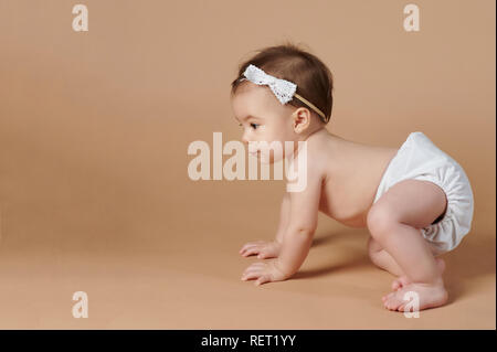 Kleines Baby kriechen auf browncolor studio Hintergrund Stockfoto