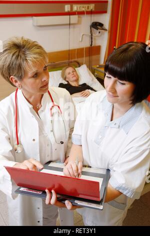 Arzt und Krankenschwester sprechen über eine Patientin in einem Krankenhaus während der Runde Stockfoto
