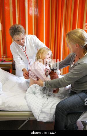 Arzt die Prüfung eines jungen Patienten, sieben Jahre alt, unterstützt durch die Mutter am Bett in einem Krankenhaus Stockfoto