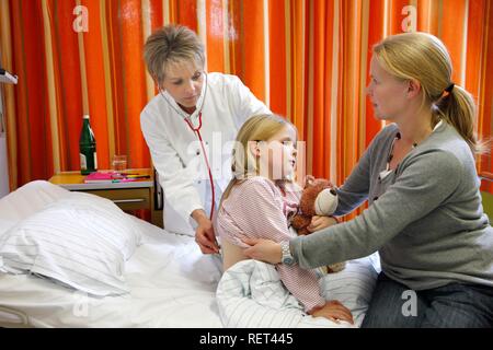 Arzt die Prüfung eines jungen Patienten, sieben Jahre alt, unterstützt durch die Mutter am Bett in einem Krankenhaus Stockfoto