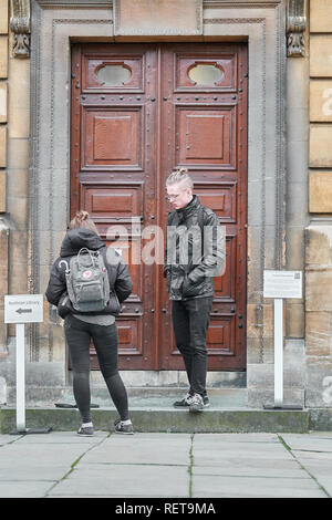 Zwei Besucher stehen und vor dem Eingang zum Sheldonian Theatre an der Universität von Oxford, England warten. Stockfoto