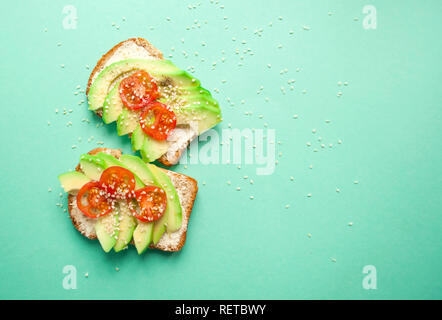 Flach an leckeren Toast mit Avocado, Tomaten in Scheiben geschnitten und gehören insbesondere Samen auf blauem Hintergrund mit Copyspace. Stockfoto
