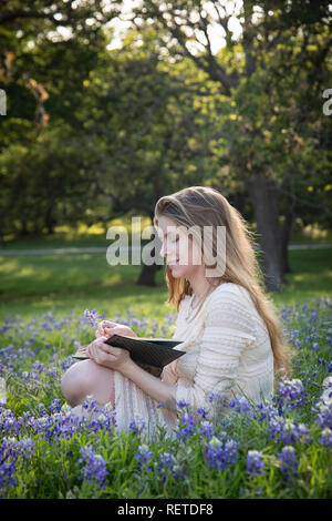 Mädchen das Lesen eines Buches in bluebonnet Blumen Stockfoto