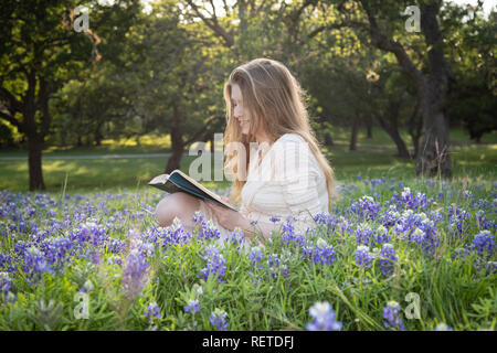 Mädchen das Lesen eines Buches in bluebonnet Blumen Stockfoto