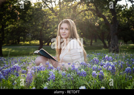 Mädchen das Lesen eines Buches in bluebonnet Blumen Stockfoto