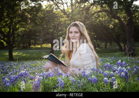 Mädchen das Lesen eines Buches in bluebonnet Blumen Stockfoto