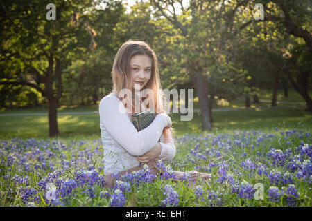 Mädchen das Lesen eines Buches in bluebonnet Blumen Stockfoto