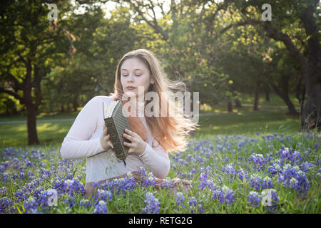 Mädchen das Lesen eines Buches in bluebonnet Blumen Stockfoto