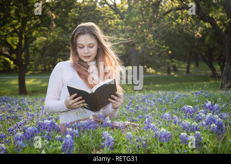 Mädchen das Lesen eines Buches in bluebonnet Blumen Stockfoto