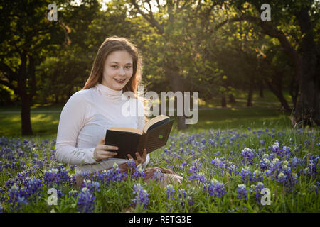 Mädchen das Lesen eines Buches in bluebonnet Blumen Stockfoto