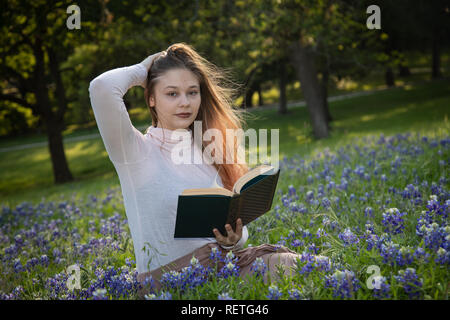 Mädchen das Lesen eines Buches in bluebonnet Blumen Stockfoto