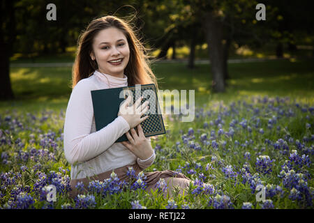 Mädchen das Lesen eines Buches in bluebonnet Blumen Stockfoto