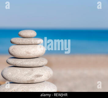 Stress locker mehrere Zen Steine auf Unscharf blaue Meer und Strand Stockfoto