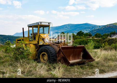 Alten, verlassenen unterbrochener gelber Bagger, in der Nähe vom See Zavoj, auf einer alten Berg. Rostig und mit der beschädigte Reifen widersetzte sich der Zahn der Zeit. Stockfoto