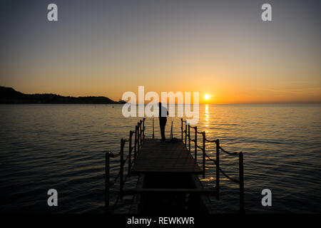 Silhouette eines Mannes fertig, zum Schwimmen im Meer bei Sonnenuntergang Stockfoto