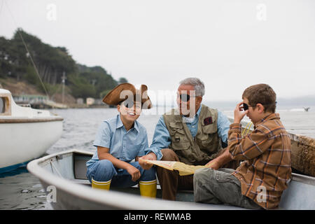 Vater sitzt in einem Ruderboot mit seinen beiden Söhnen gekleidet als Piraten. Stockfoto
