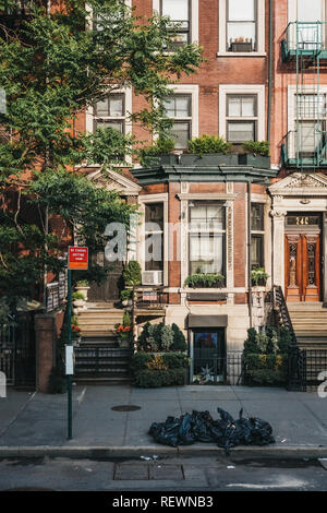 New York, USA - 30. Mai 2018: Fassade eines typischen New Yorker Haus mit einem Stoop, Müll in schwarz Fächer vor. Die Stadt erzeugt mehr als 11,0 Stockfoto