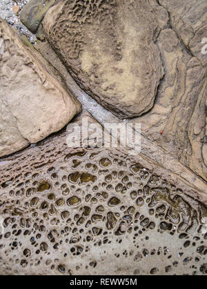 Semi-abstrakten Detail eines nassen, erodiert braun Sandstein Strand, mit diagonalen Linie der Sand zwischen den Felsen (vertikal, Britische Coumbia). Stockfoto