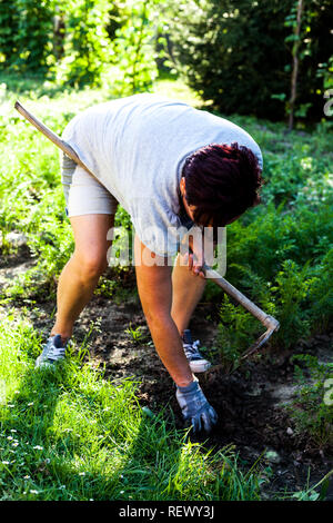 Die fleissigen Gärtner pflügen. Die Frau biegen und Entfernen von Unkraut aus dem Boden. Vorbereitung für die Zeit der Aussaat. Landwirtschaft und Garten Stockfoto