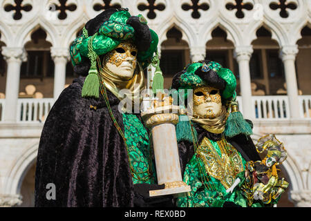 Karneval in Venedig. Zwei wunderschöne venezianische Masken mit Saint Mark Lion Spalte vor der Dogenpalast Stockfoto