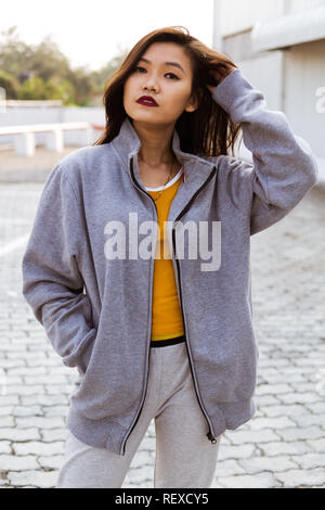 Junge Frau, die die Kamera in der Nähe eines städtischen Struktur darstellen. Stockfoto