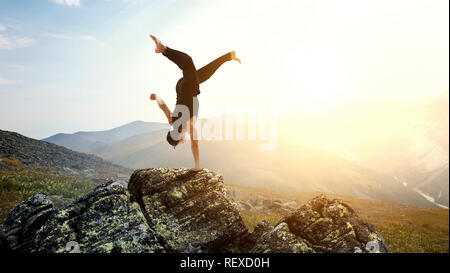 Erstaunlich yoga Mann sie einen Handstand auf Rock. Mixed Media Stockfoto