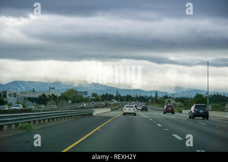 März 26, 2017, San Jose/CA/USA - das Fahren auf der Autobahn über Silicon Valley an einem stürmischen Frühling, Strahlen des Lichts und der Regen in der Ferne Stockfoto