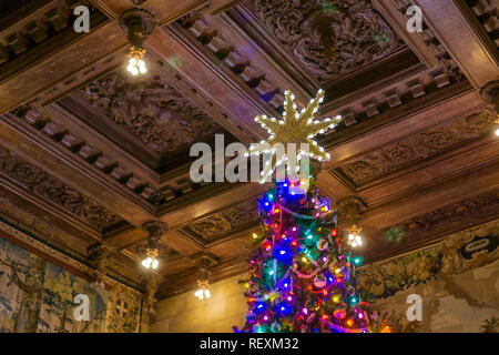 Dezember 23, 2017, San Simeon/CA/USA - Weihnachtsbaum Stern auf einem geschmückten Baum; antike Holzdecke im Hintergrund; Hearst Castle Stockfoto