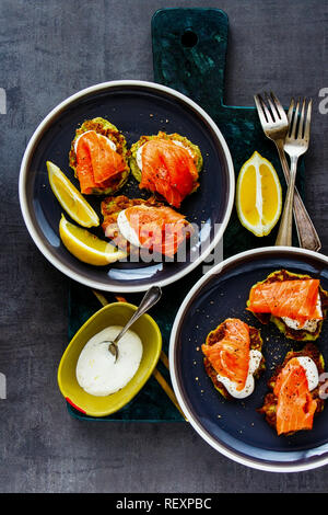 Frische zucchini Krapfen mit Crème fraîche und Lachs auf Platte flach-lay Stockfoto