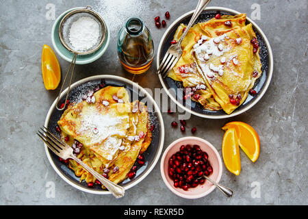 Süßen Crepes gefüllt mit Granatapfel und Zucker. Dünne Pfannkuchen, Obst und Ahornsirup Flachbild-lay Stockfoto