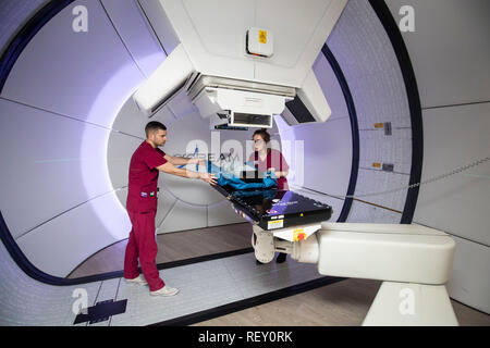 Die Radiographen David Kirk (links) und Melissa Bentley (rechts) zeigen mit einem Testdummy das neue Proton Beam-Therapiezentrum des NHS im Krankenhaus Christie in Manchester, als sich der 15-jährige Mason Kettley (nicht abgebildet), der einen seltenen Hirntumor hat, auf die weltweit führende Behandlung vorbereitet. Stockfoto