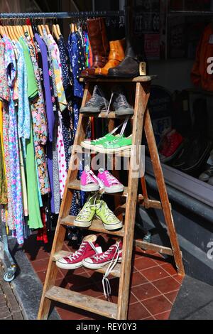 Eine bunte Anzeige von Schuhen und Stiefeln für den Verkauf außerhalb ein Schuhgeschäft in Amsterdam, Holland, in witziger Art und Weise auf jeder Sprosse der Leiter vorgestellt. Stockfoto