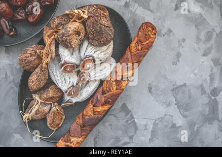 Getrocknet, Kaki, Feigen, Melone auf einem schwarzen Schild auf einem hölzernen Hintergrund. Close-up. Kopieren Sie Platz. Selektiver Fokus Stockfoto